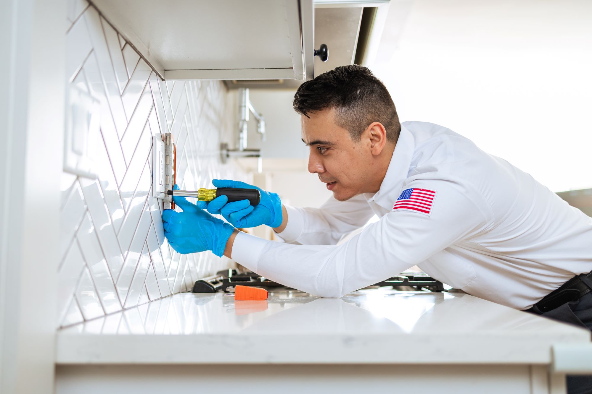 Electrician in Mister Sparky uniform working on an outlet.
