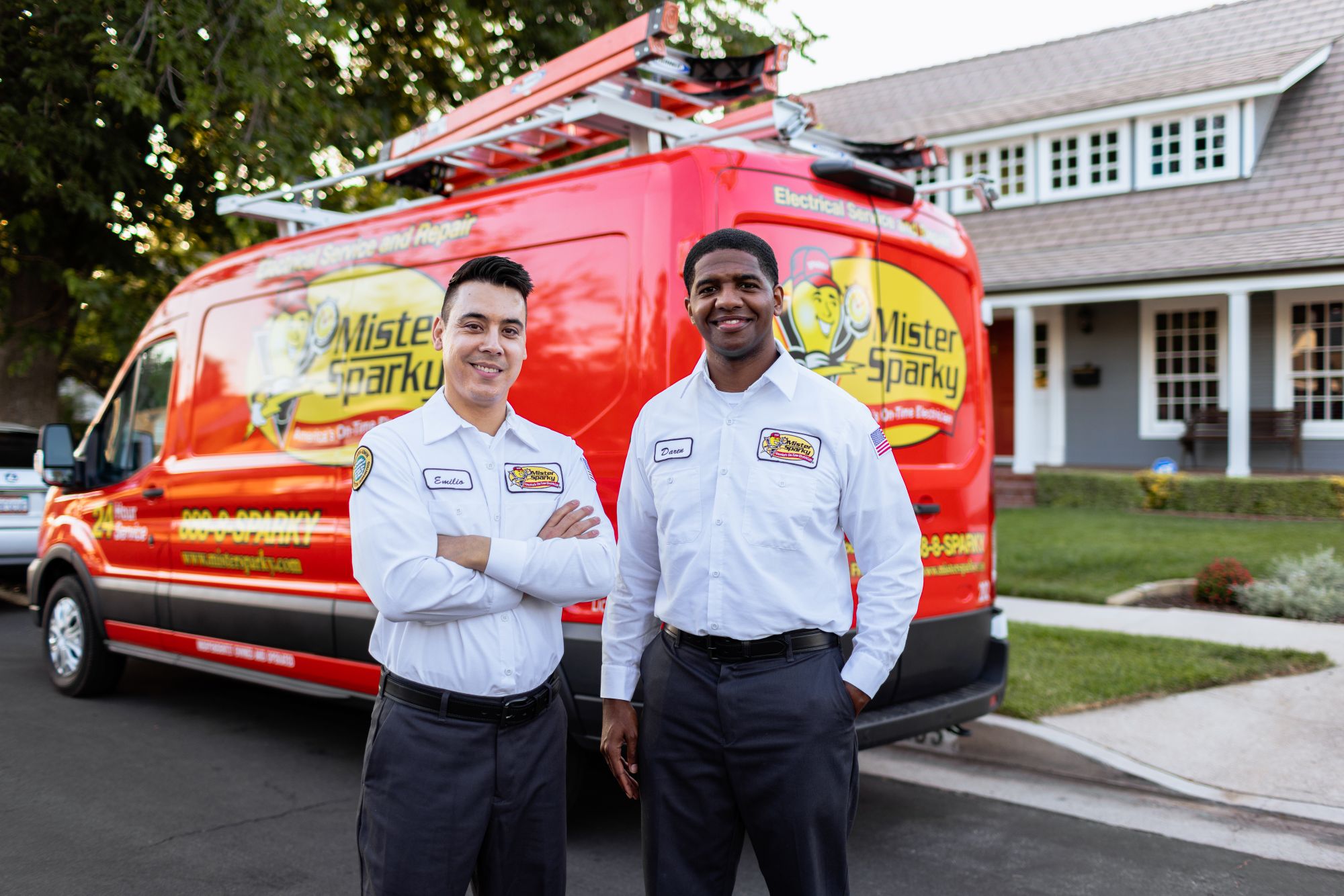 Two Mister Sparky franchise owners standing in front of a branded van.